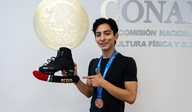 Donovan Carrillo, seleccionado mexicano de patinaje artístico sobre hielo, luce su medalla de bronce y los patines con los que ganó su pase olímpico.