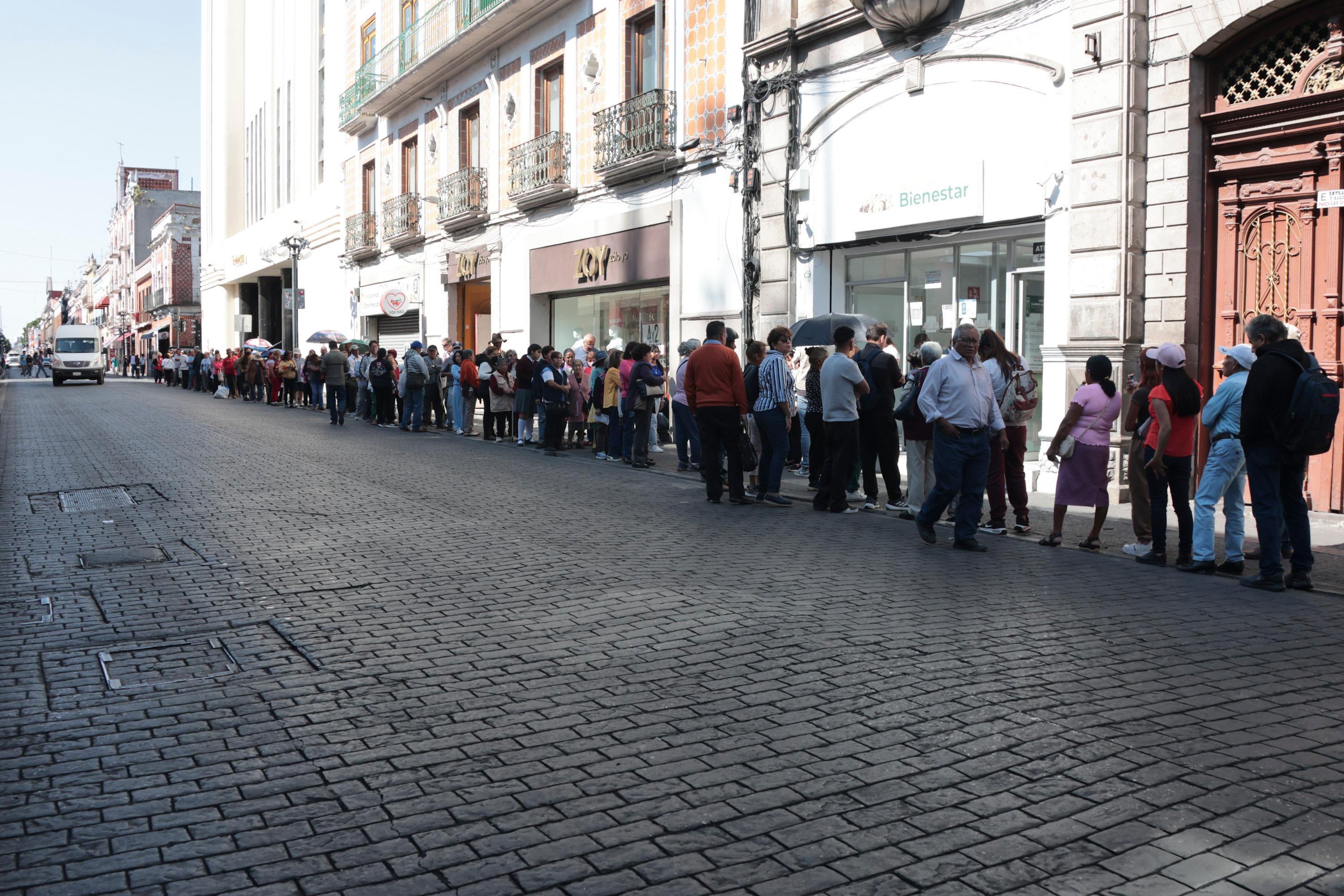 Largas filas para el Banco del Bienestar en avenida Reforma en el Centro Histórico de la ciudad de Puebla.